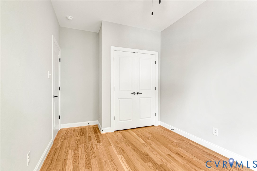 Hardwood flooring, painted walls, white trim, and white paneled doors
