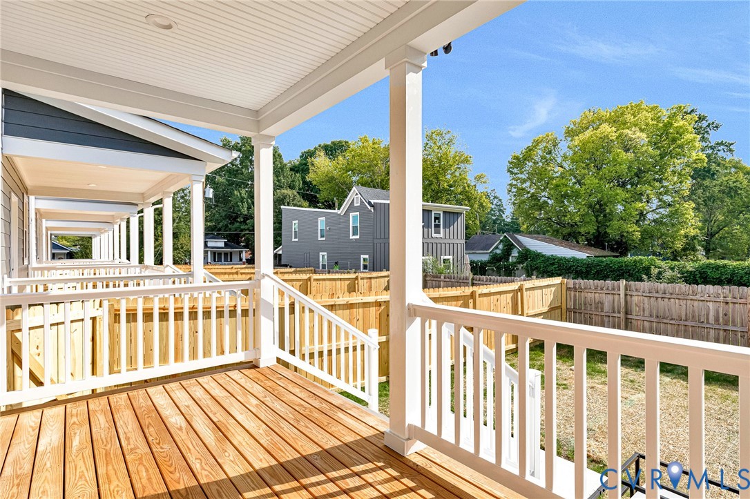 Expansive covered deck featuring white composite railings, wood-finish decking, and white support columns
