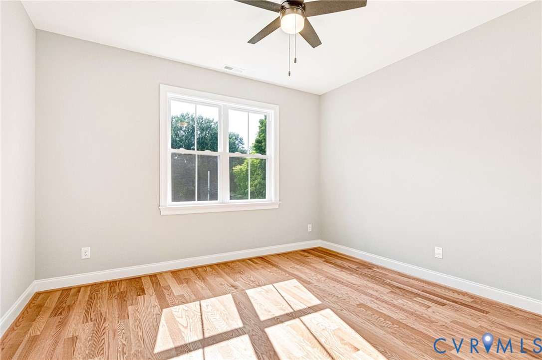 Hardwood-finish flooring, white trim, ceiling fan, and a double-hung window