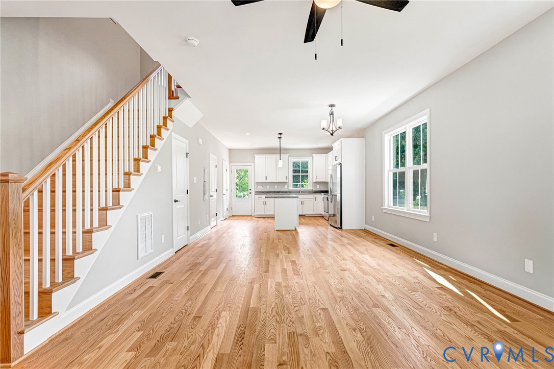 Hardwood flooring, white painted walls, white kitchen cabinetry, stainless steel appliances, and a central island Hardwood flooring, white painted walls, white kitchen cabinetry, stainless steel appliances, and a central island