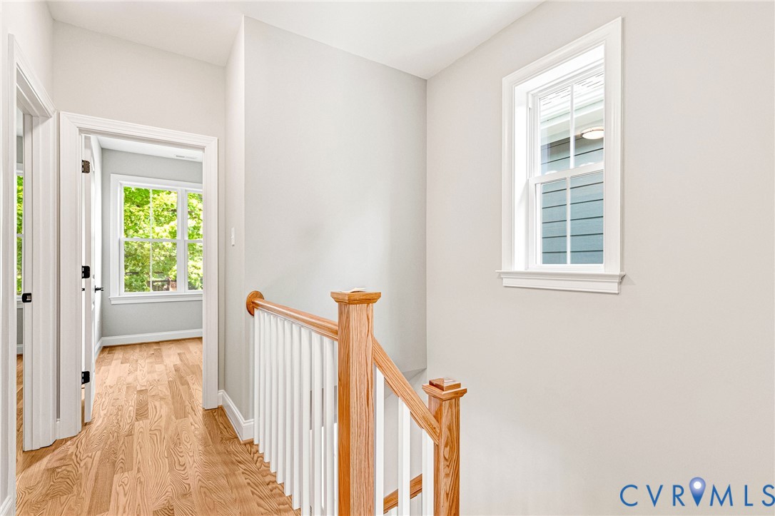 Hardwood flooring, painted walls, white trim, wood handrail, white balusters, and a double-hung window