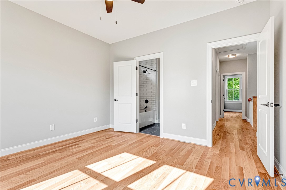 Wood-finish flooring, white paneled doors, ceiling fan, and light gray wall paint
