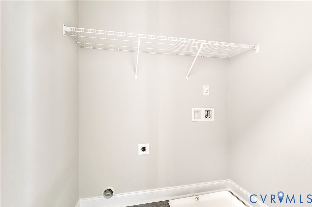 Dedicated laundry space with light gray walls, white wire shelving, utility hookups, and a utility sink