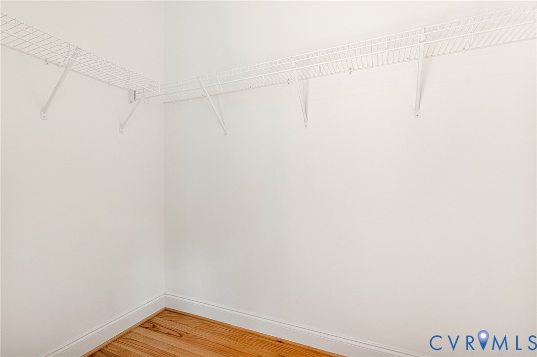 Corner closet featuring wire shelving and wood-finish flooring