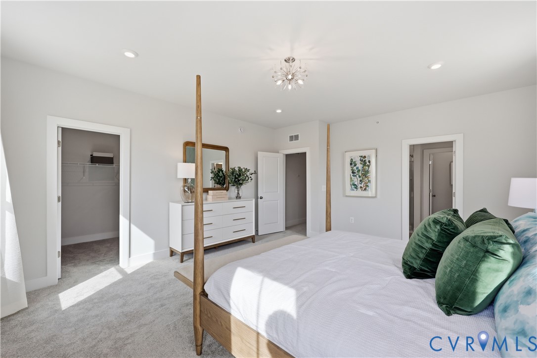 Spacious room featuring light gray carpeting, recessed lighting, and a modern chandelier