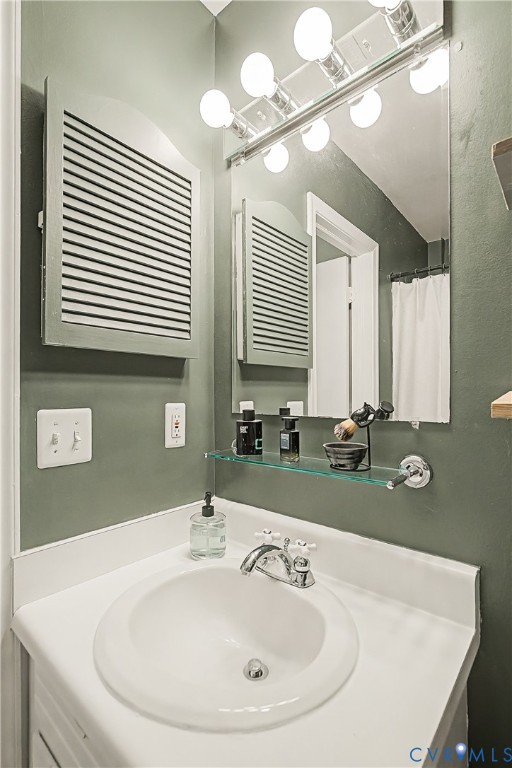 White vanity countertop with an integrated basin, chrome two-handle faucet, wall-mounted mirror, and vanity lighting fixture