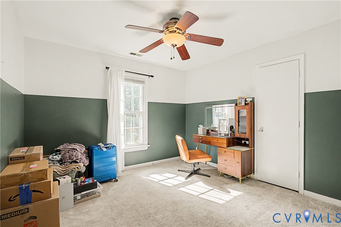 White walls with a contrasting green wainscoting, ceiling fan, and carpeted flooring