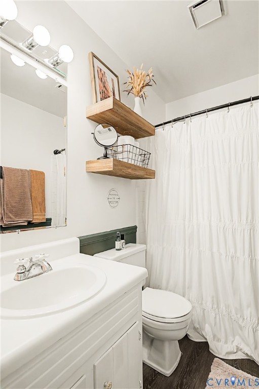 Vanity with integrated sink, wood-finish flooring, two floating shelves, and a white shower curtain
