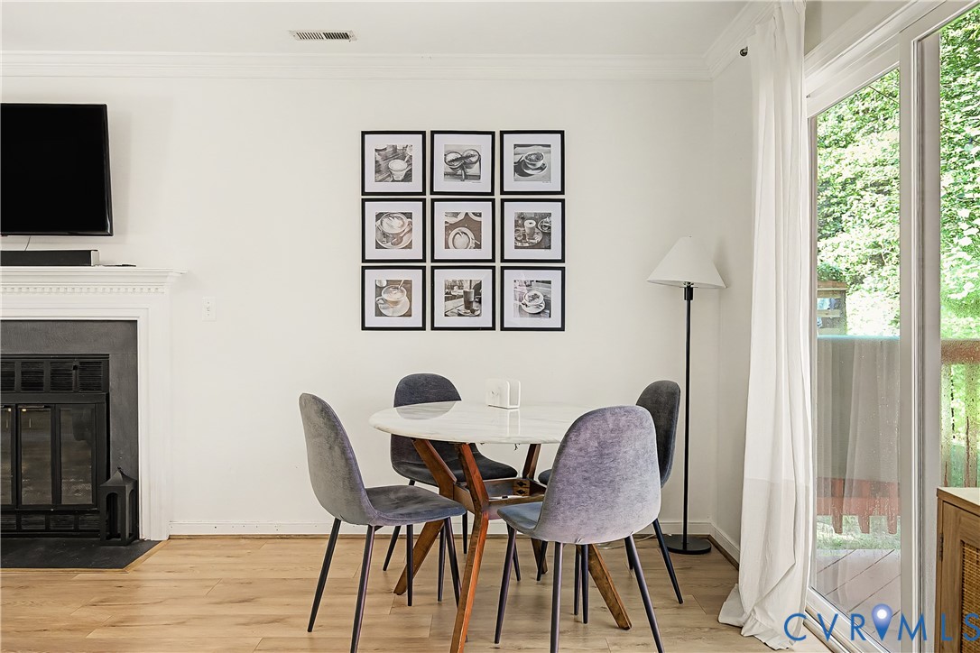 Fireplace with a detailed mantelpiece, light wood-finish flooring, and a glass sliding door