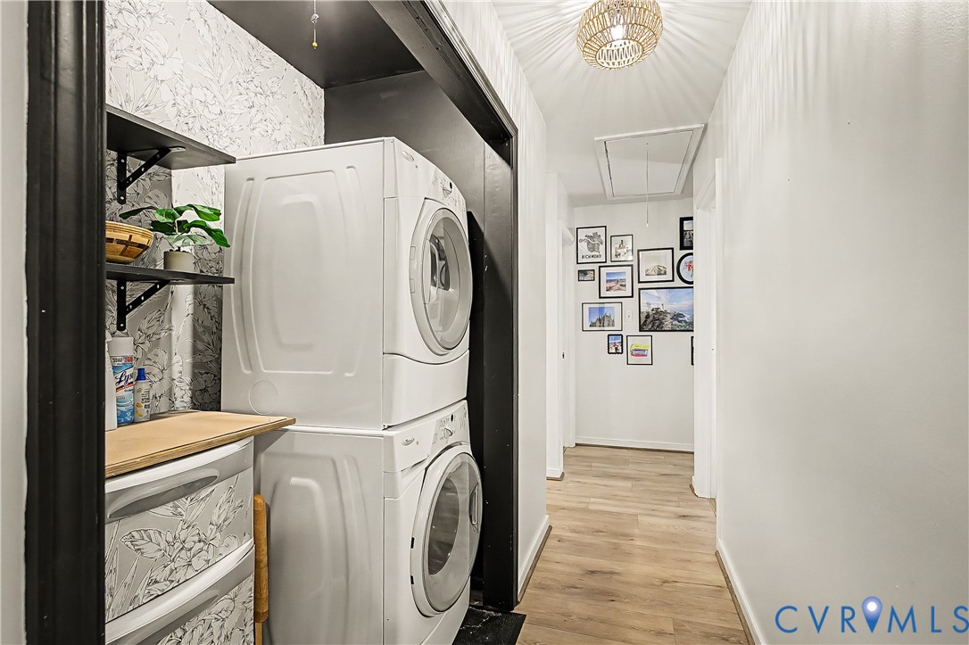 Integrated laundry area featuring stacked appliances and open shelving