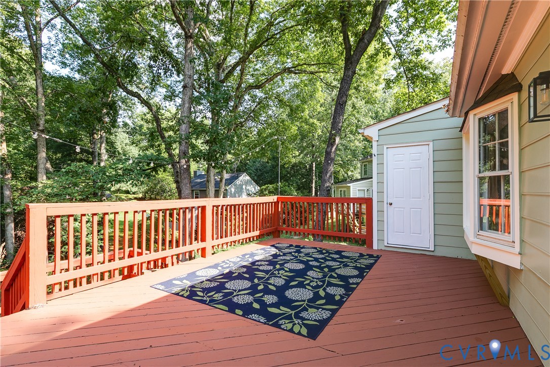 Expansive outdoor deck with wood railing, offering a separate exterior entrance and a bay window