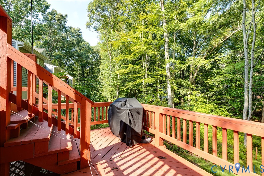 Multi-level wood deck with wood railings, featuring a treed backdrop