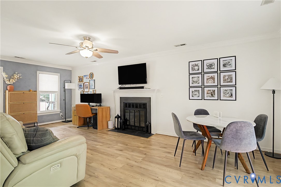 Wood-finish flooring throughout, ceiling fan with integrated lighting, built-in fireplace, and a dining area
