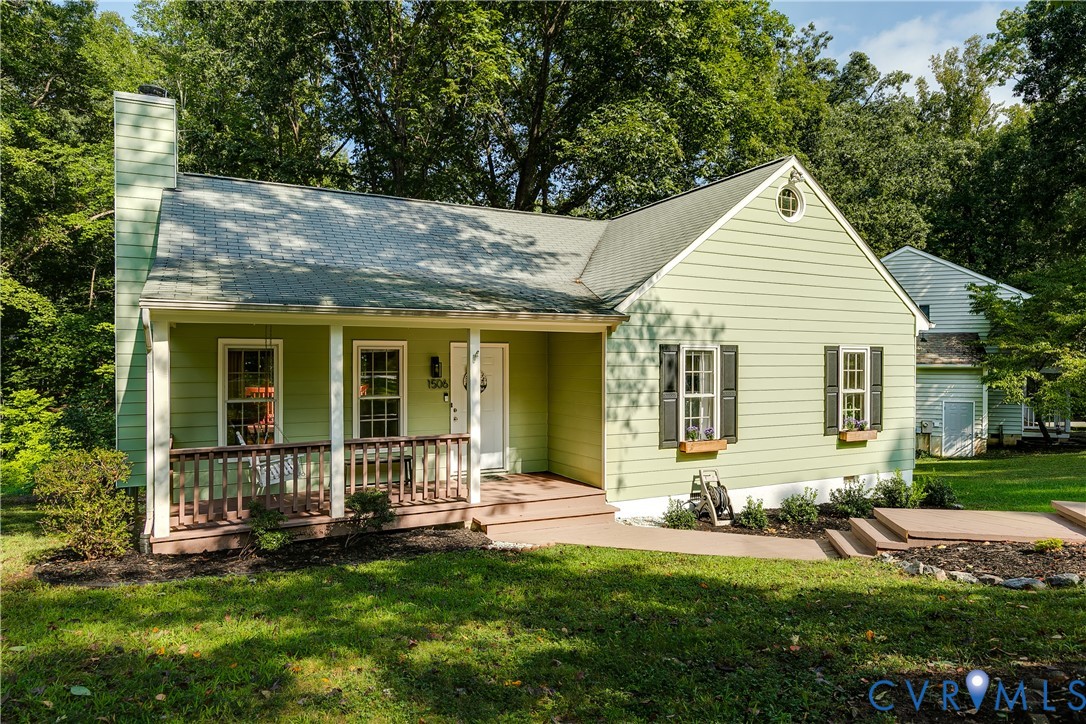 Gabled roofline residence featuring light green siding, a covered front porch, and a side chimney