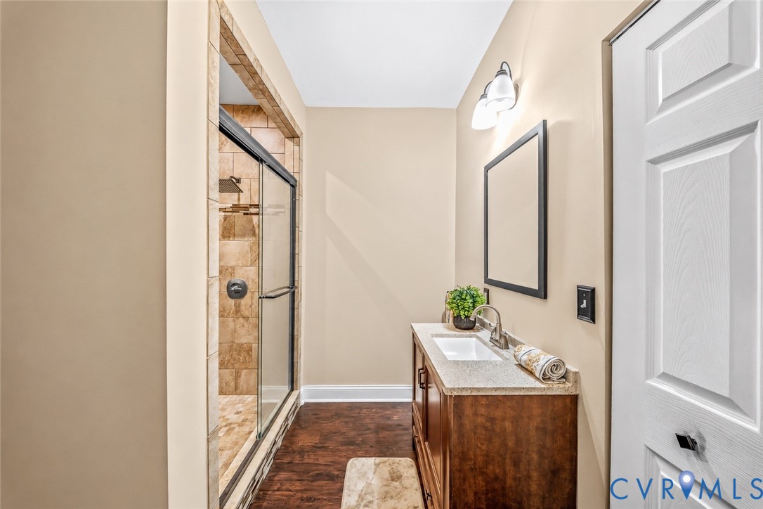 Shower with a sliding glass door and stone-tiled walls