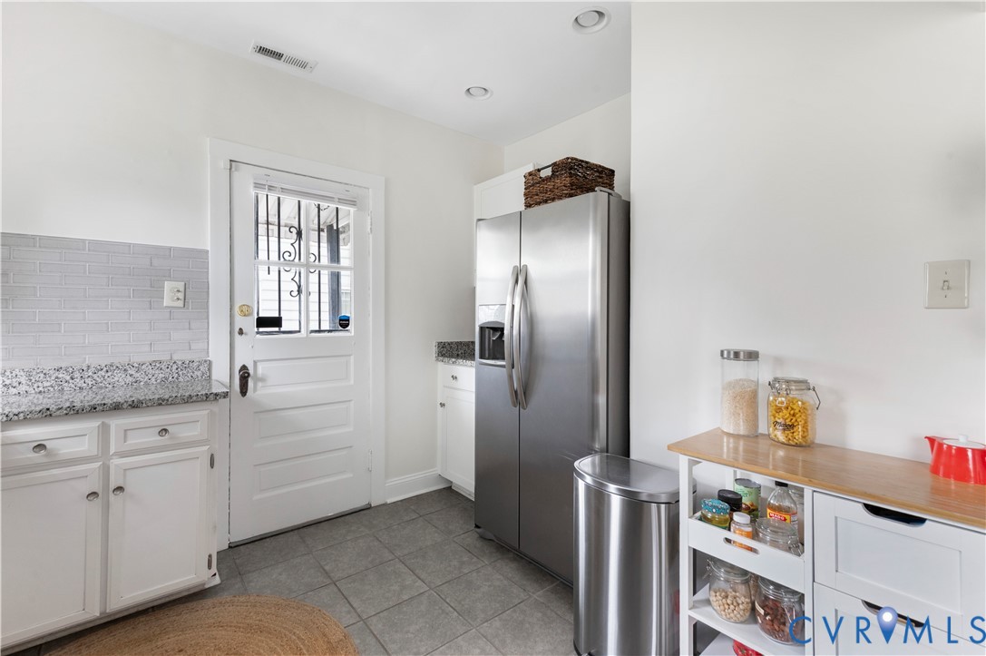 Kitchen featuring white cabinetry, gray subway tile backsplash, speckled countertops, and gray tile flooring Kitchen featuring white cabinetry, gray subway tile backsplash, speckled countertops, and gray tile flooring