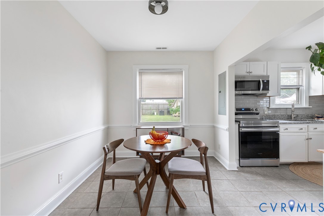 Bright breakfast nook featuring a round pedestal table, wood chairs, and large window with natural light Bright breakfast nook featuring a round pedestal table, wood chairs, and large window with natural light