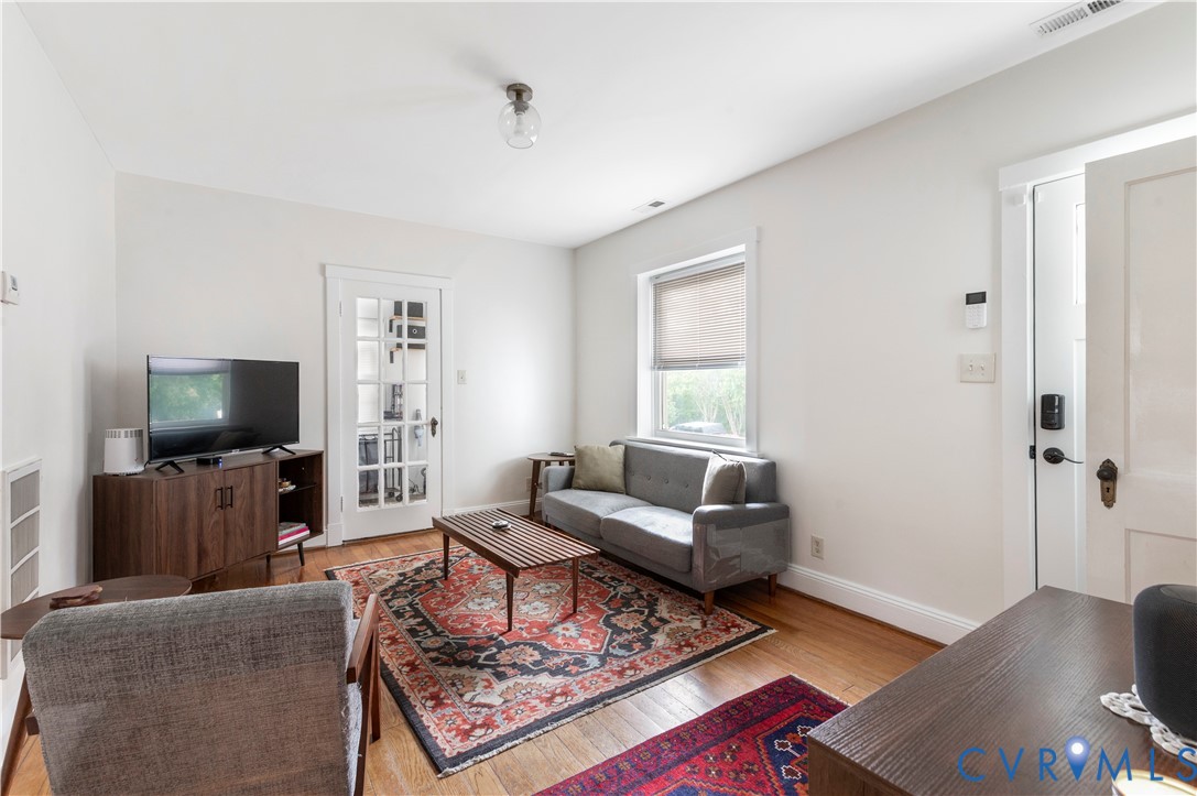 Hardwood flooring, white walls, and a window with blinds