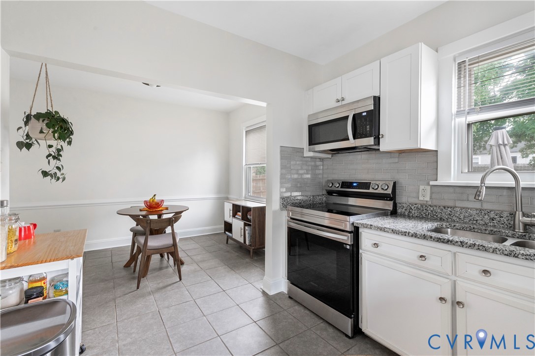 Kitchen featuring white cabinetry, stainless steel appliances, a tiled backsplash, and stone countertops