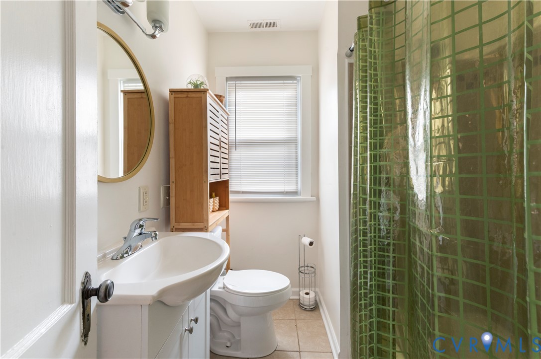 White vanity with integrated sink, chrome faucet, and gold-framed circular mirror