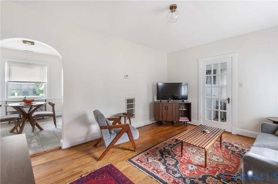 Wood-finish flooring, white painted walls, and an arched doorway