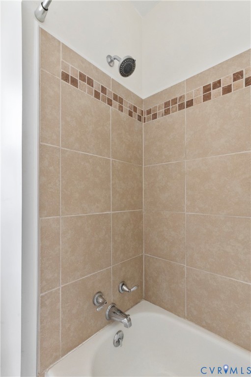 Tiled shower surround with decorative accent band and chrome fixtures