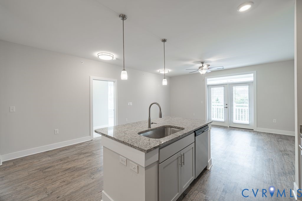 Kitchen island with granite countertop, integrated sink, and stainless steel dishwasher