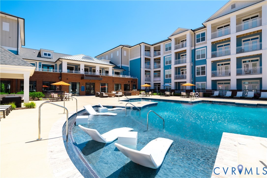 Outdoor swimming pool with integrated lounge seating, surrounded by a light-colored concrete deck