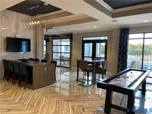Glossy tile flooring, tray ceiling with recessed lighting, full-height windows, and a glass-paneled door