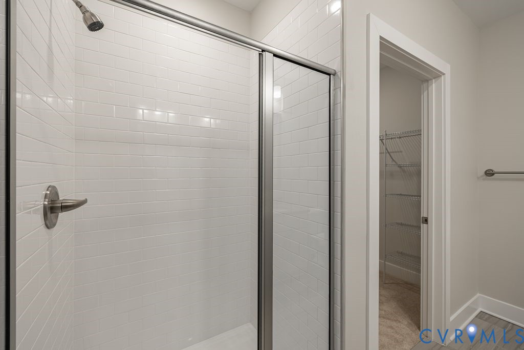 Glass-enclosed shower with subway tile surround, brushed nickel hardware, and a rainfall showerhead