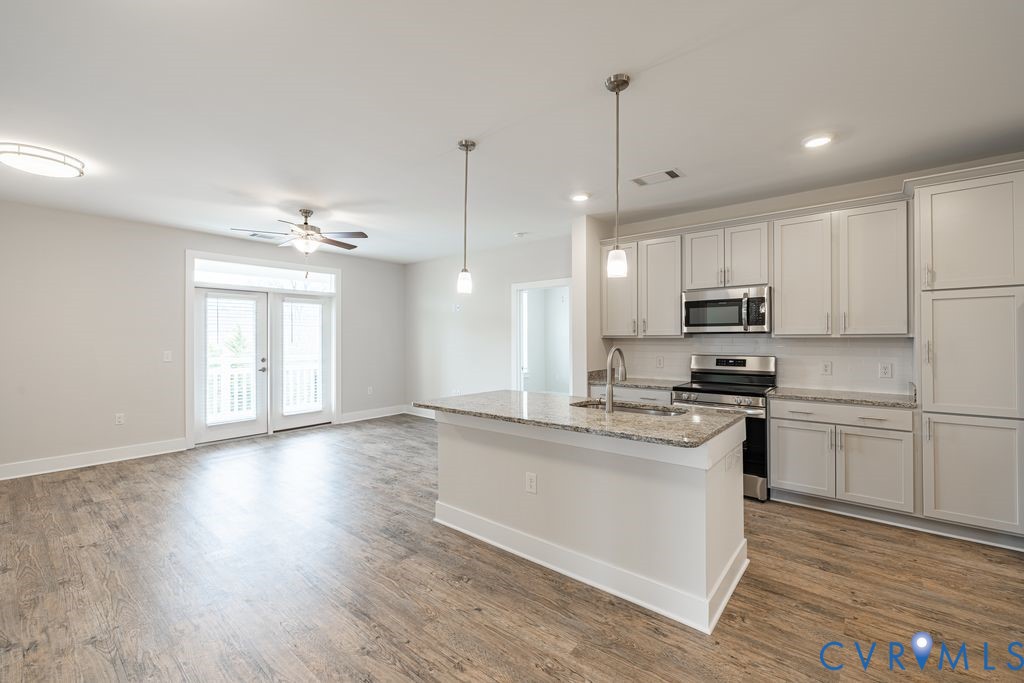 Open-concept living area featuring wood-finish flooring, a contemporary ceiling fan, and double French doors