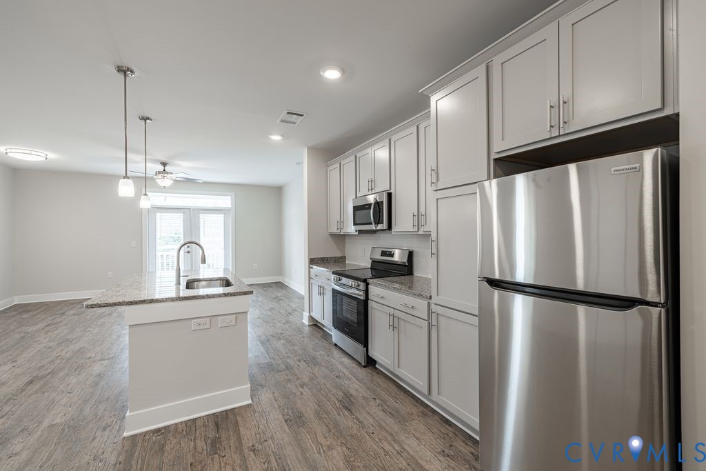 Kitchen featuring stainless steel appliances, light-toned cabinetry, and wood-finish flooring