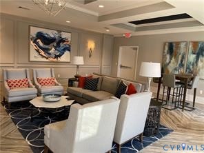 Wainscoting paneling, multi-layered tray ceiling, contemporary chandelier, recessed lighting, and wood-finish flooring