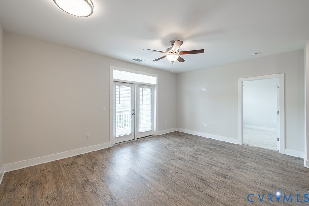 Wood-finish flooring, ceiling fan with integrated lighting, recessed ceiling light, white trim, and double glass doors