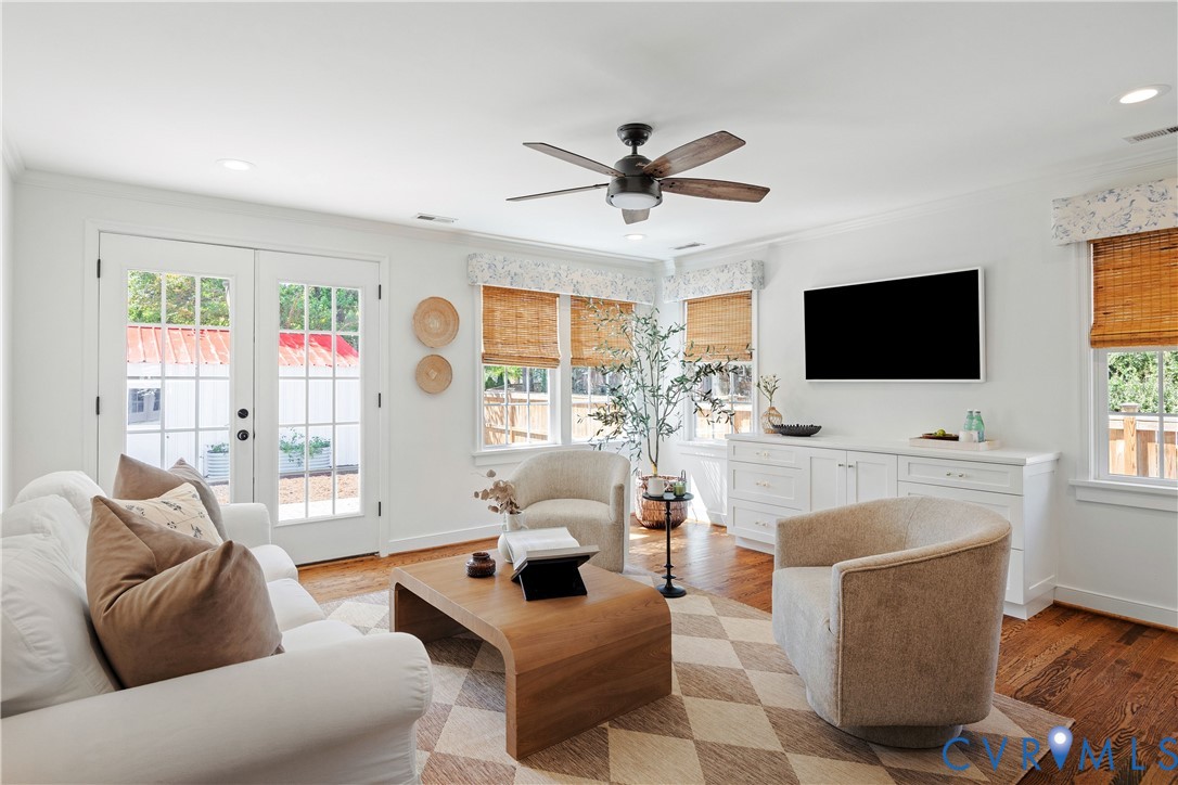 Hardwood flooring, recessed lighting, ceiling fan, white paneled French doors, and built-in cabinetry