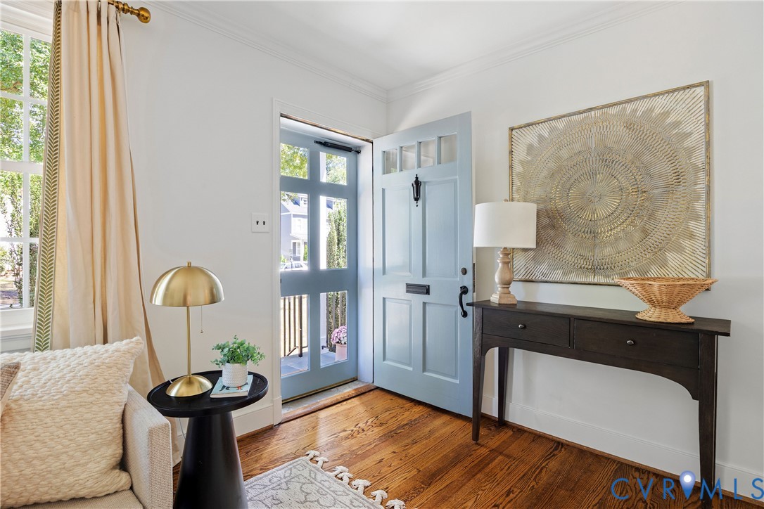 Light blue paneled entry door with transom windows, wood-finish flooring, and a console table