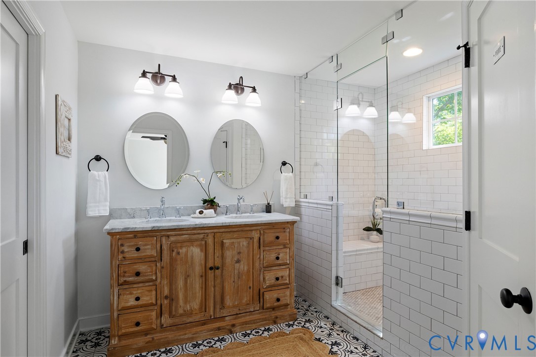 Double vanity with a light-toned wood finish and a stone countertop
