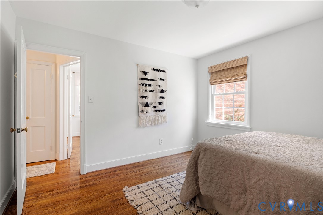 Hardwood flooring, white painted walls, white trim, recessed lighting, and a window with a woven shade