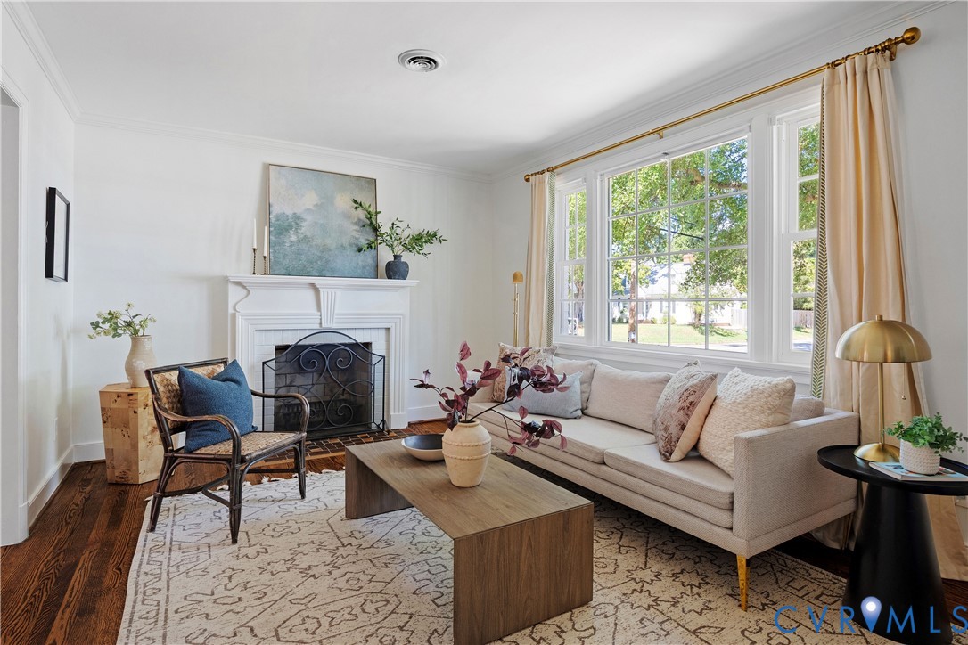 Living space featuring a white mantel fireplace, dark wood-finish flooring, and large multi-pane windows