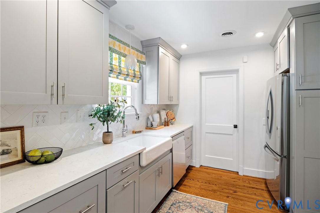 Wood-finish flooring, white countertops, farmhouse sink, stainless steel appliances, and recessed lighting