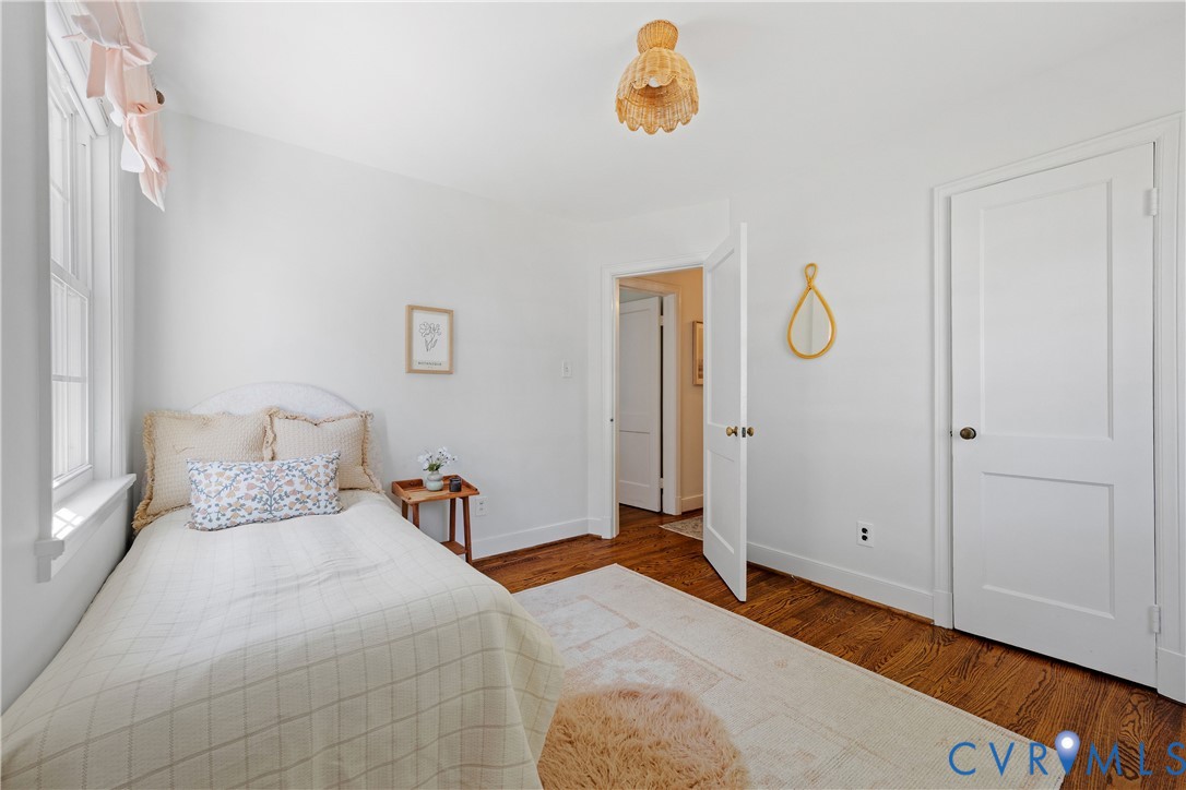 Hardwood flooring, white painted walls, white trim, white panel doors, and a decorative ceiling fixture