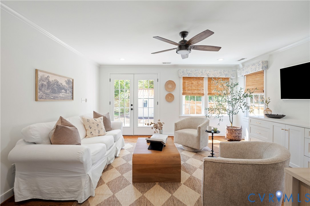 Dual pane French patio doors, wood-finish flooring, built-in cabinetry, and a ceiling fan with integrated lighting