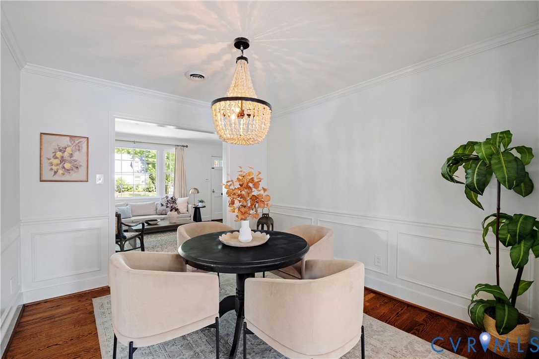 Hardwood flooring, decorative wainscoting, crown molding, and a crystal chandelier