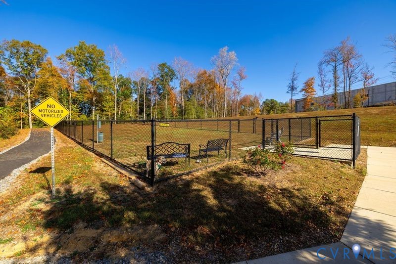 Fenced outdoor recreation area with paved pathways and mature trees
