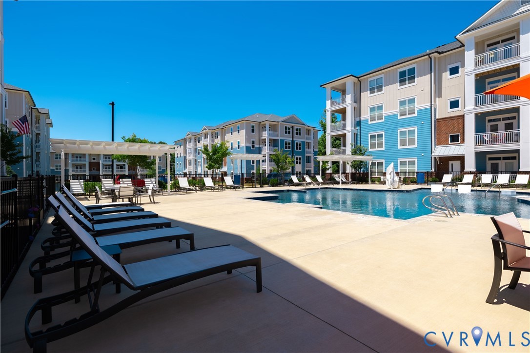 Outdoor swimming pool with integrated steps, surrounding paved patio, and white pergolas Outdoor swimming pool with integrated steps, surrounding paved patio, and white pergolas