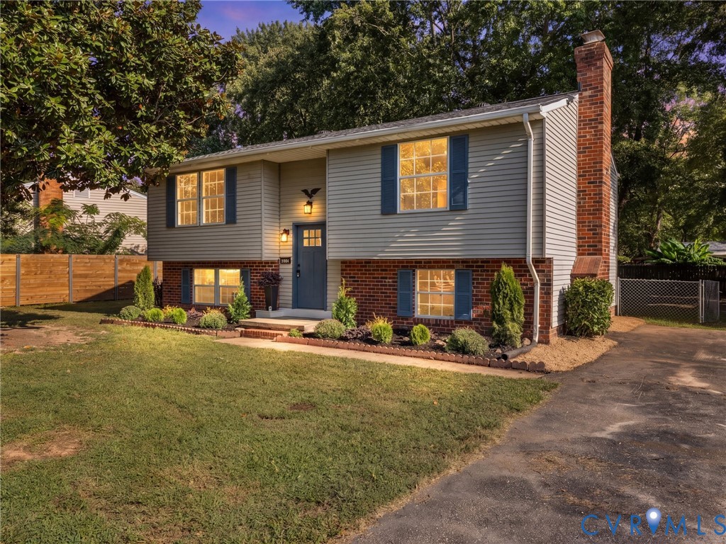 Split-level exterior featuring brick and siding, a prominent brick chimney, a driveway, and established landscaping Split-level exterior featuring brick and siding, a prominent brick chimney, a driveway, and established landscaping