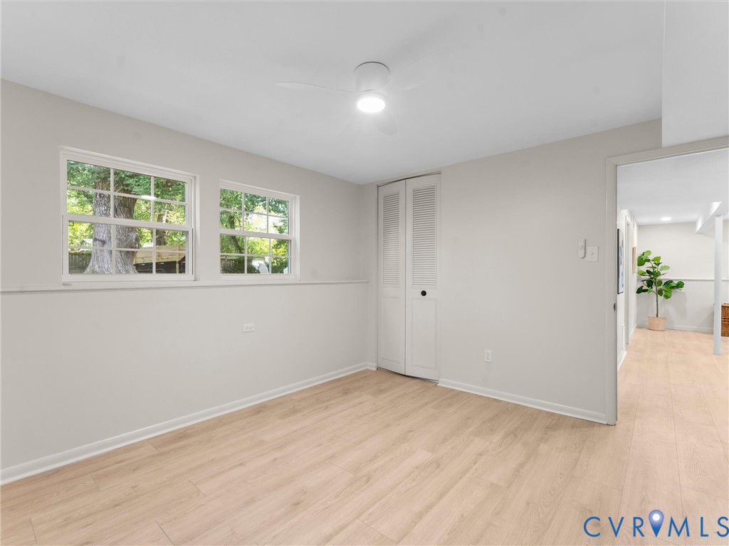 Light wood-finish flooring, white walls, and a ceiling fan