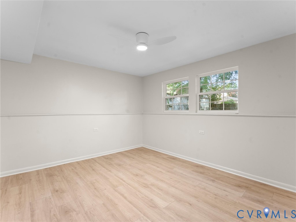 Wood-finish flooring, two large windows with natural light, a ceiling-mounted light fixture, and neutral wall tones