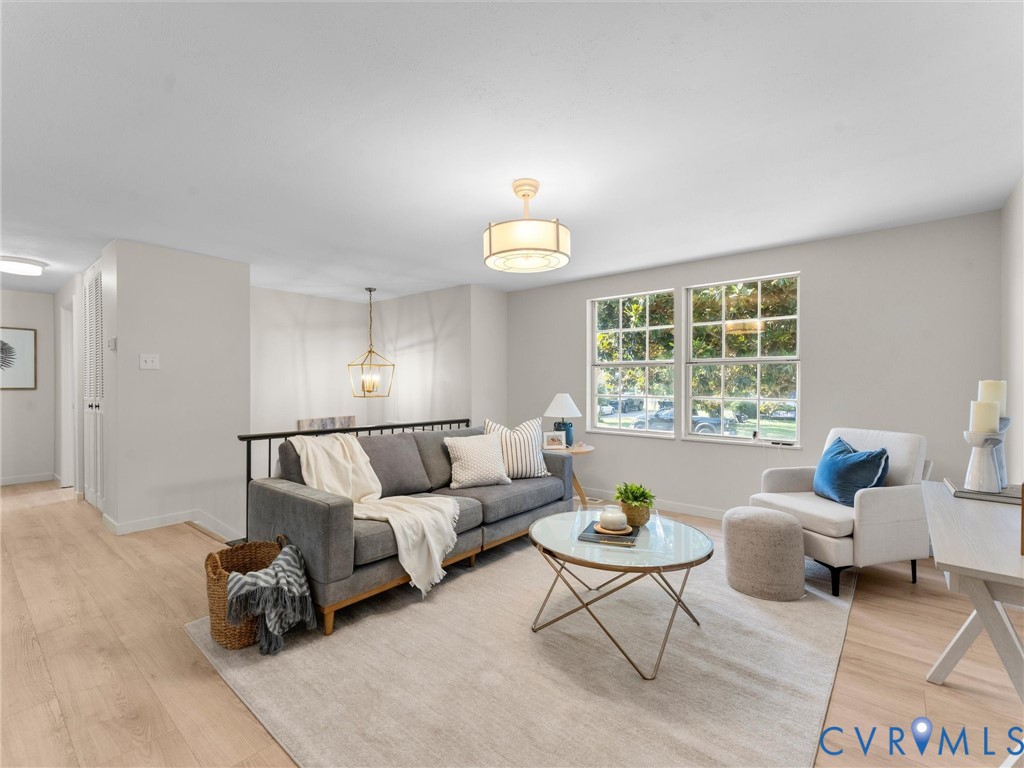 Light wood-finish flooring, dual windows with grid panes, a drum-style ceiling fixture, and a black metal railing