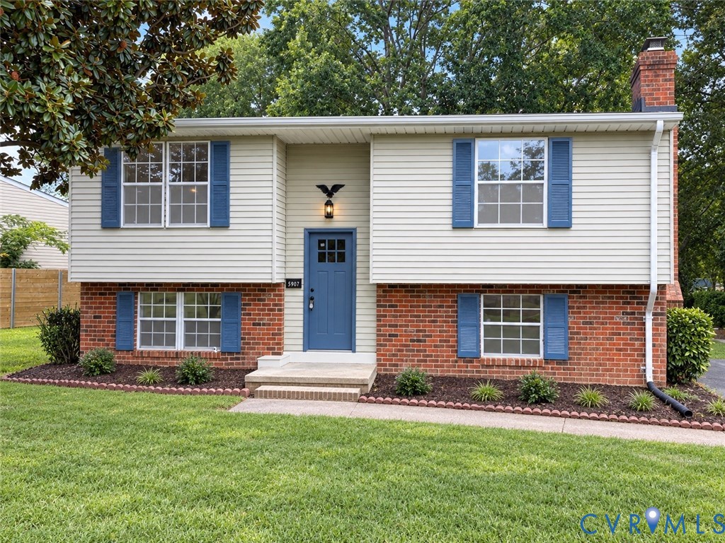Split-level residence featuring a brick foundation and light-colored siding
